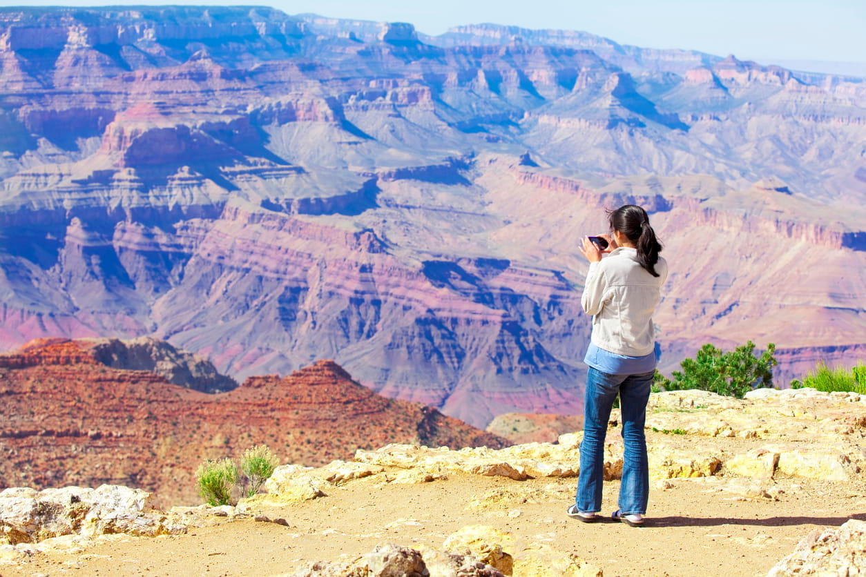 A woman takes photos of the Grand Canyon.