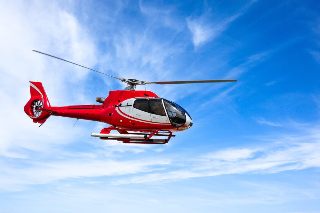 Things to do in Las Vegas for families, this is an image of a red helicopter in the air mid-tour.