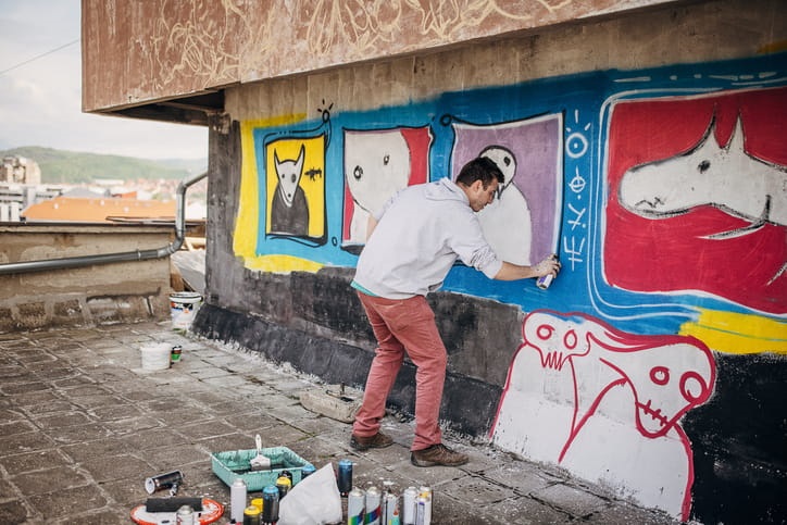 A male artist using a spray can to create street art.